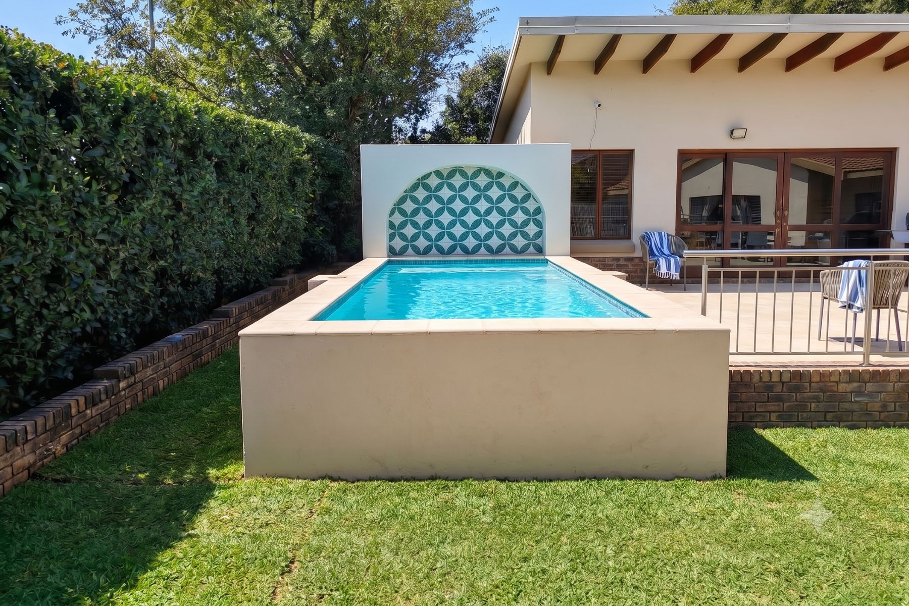 Raised pool with a patterned tile arch on a green lawn