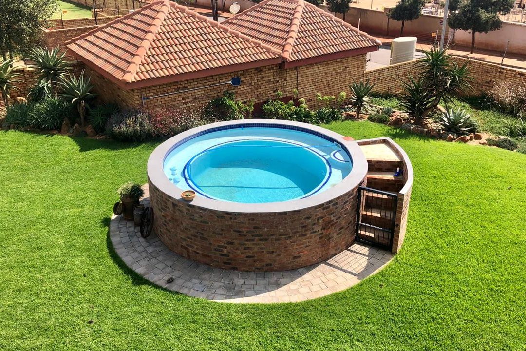Round raised brick pool on a green lawn