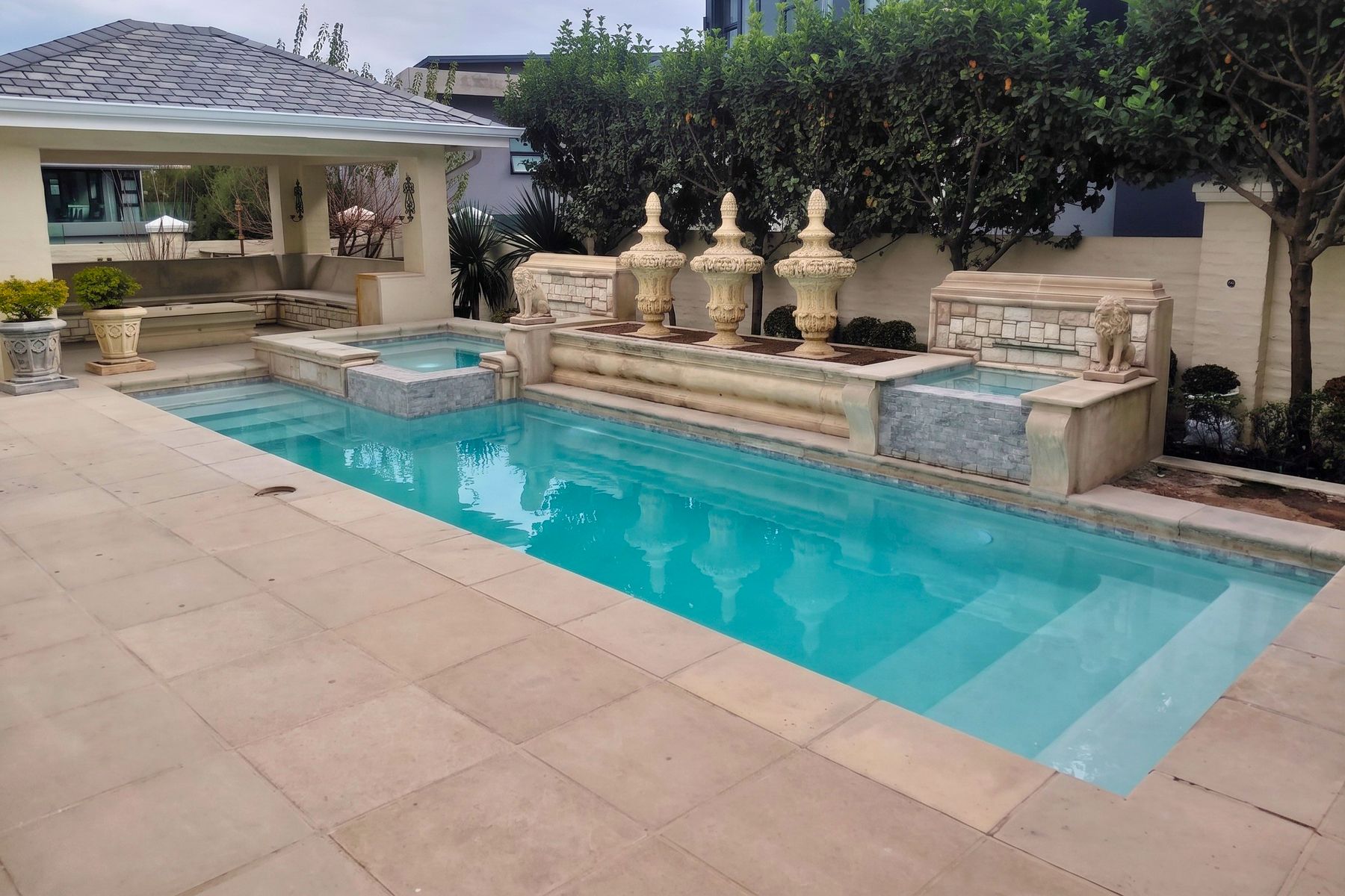 Classical pool with stone urns, lion statues and twin spill-over spas